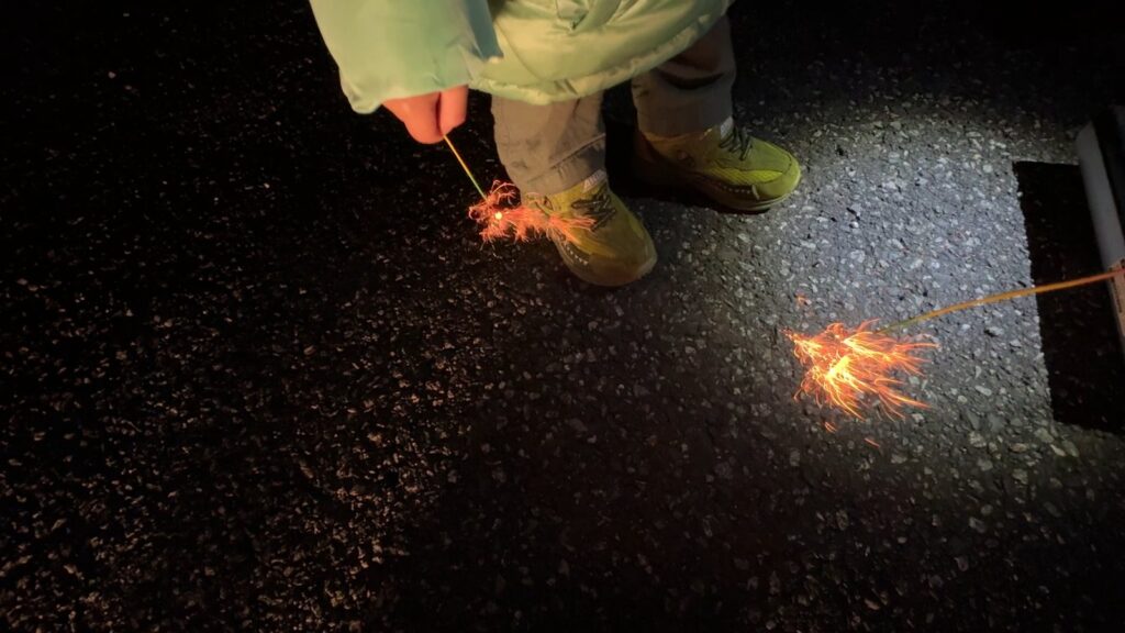 夜のキャンプ場で花火を楽しむ子どもたち