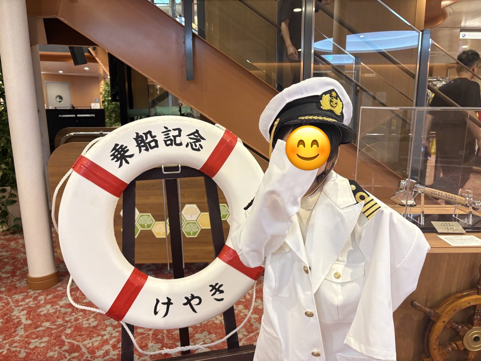 船長の制服を着て、そでで顔をかくしてポーズする娘