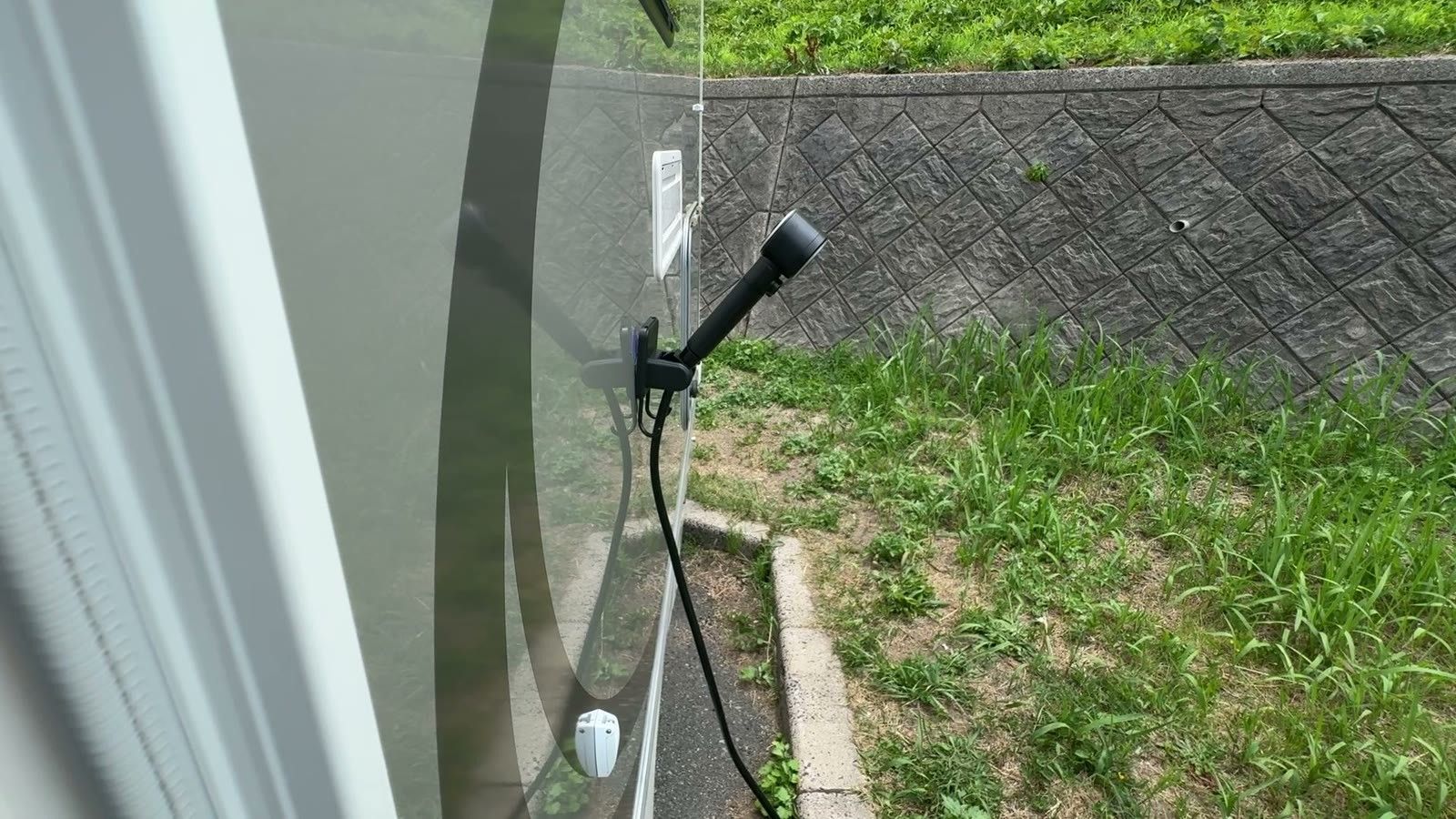 キャンピングカーの側面にホルダーで掛けたシャワーヘッド