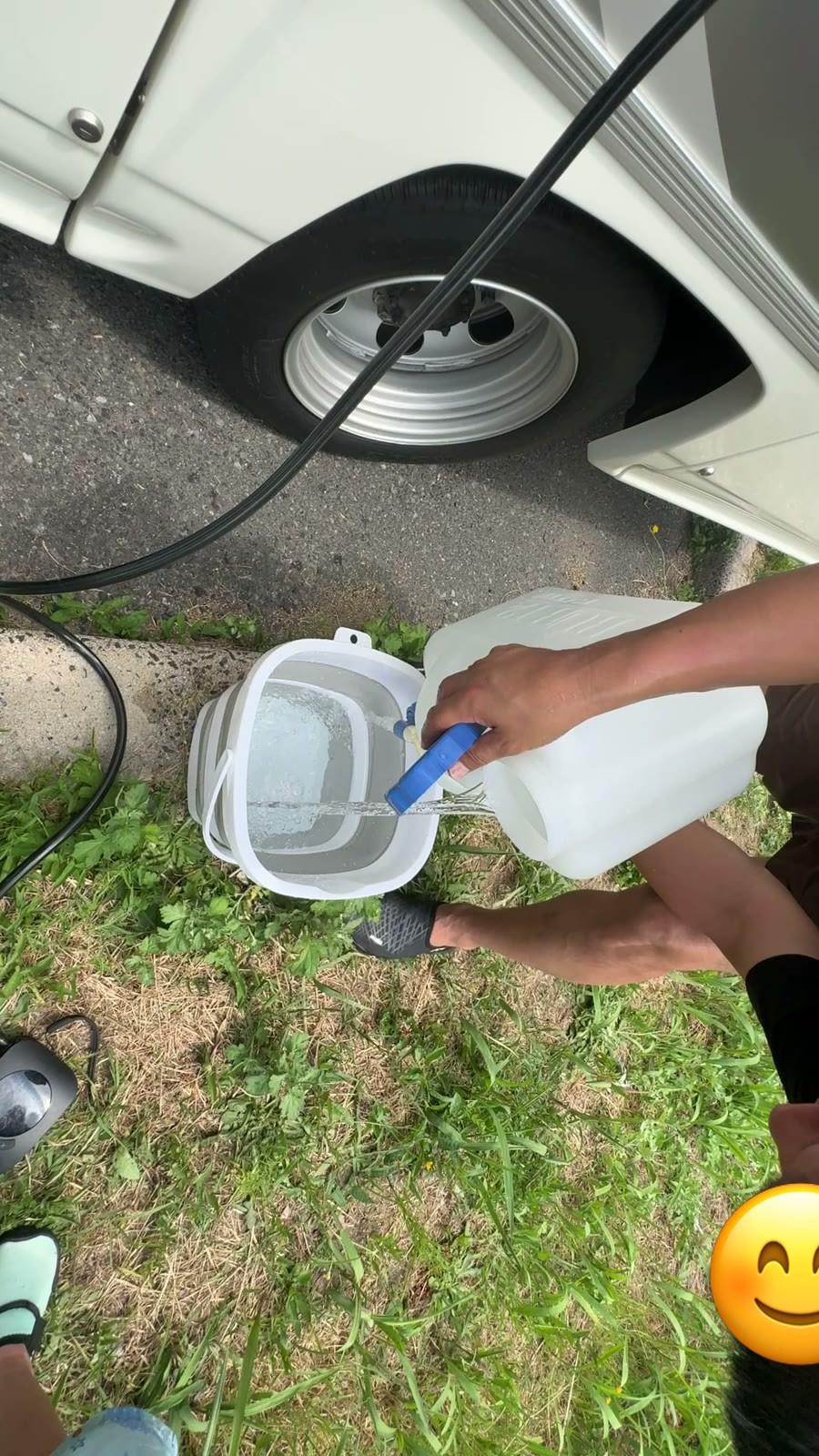 ポリタンクの水を折りたたみバケツに注ぐ様子