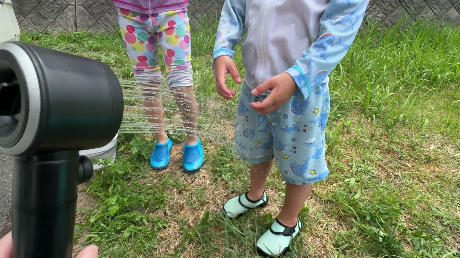ポータブルシャワーの水で砂を流す子どもの足元