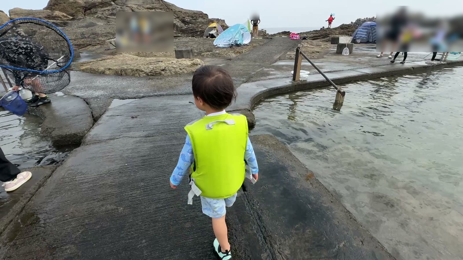ライフジャケットを着てプール横の通路を歩く3歳の息子