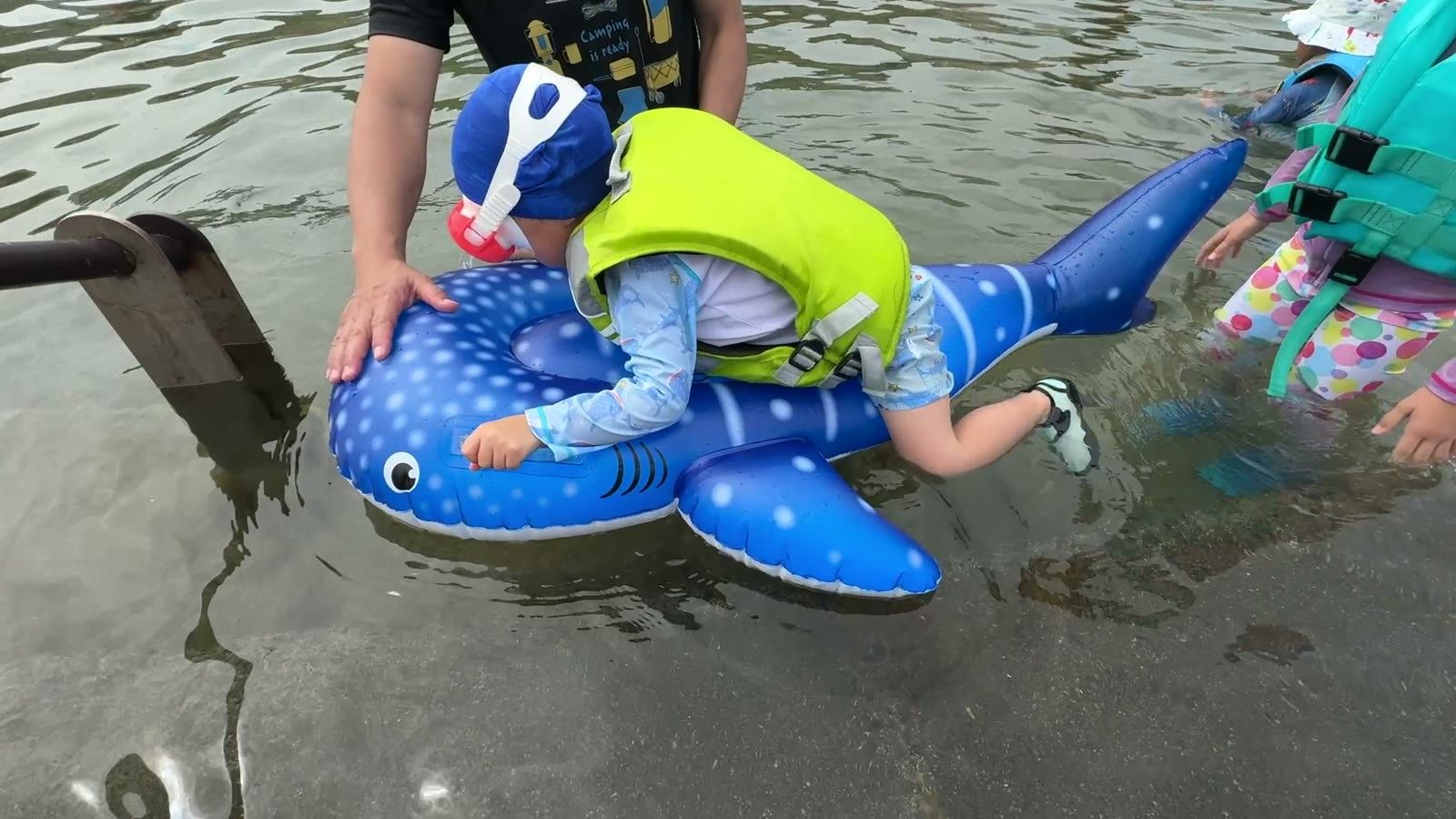 ジンベエザメの浮き輪に乗る息子