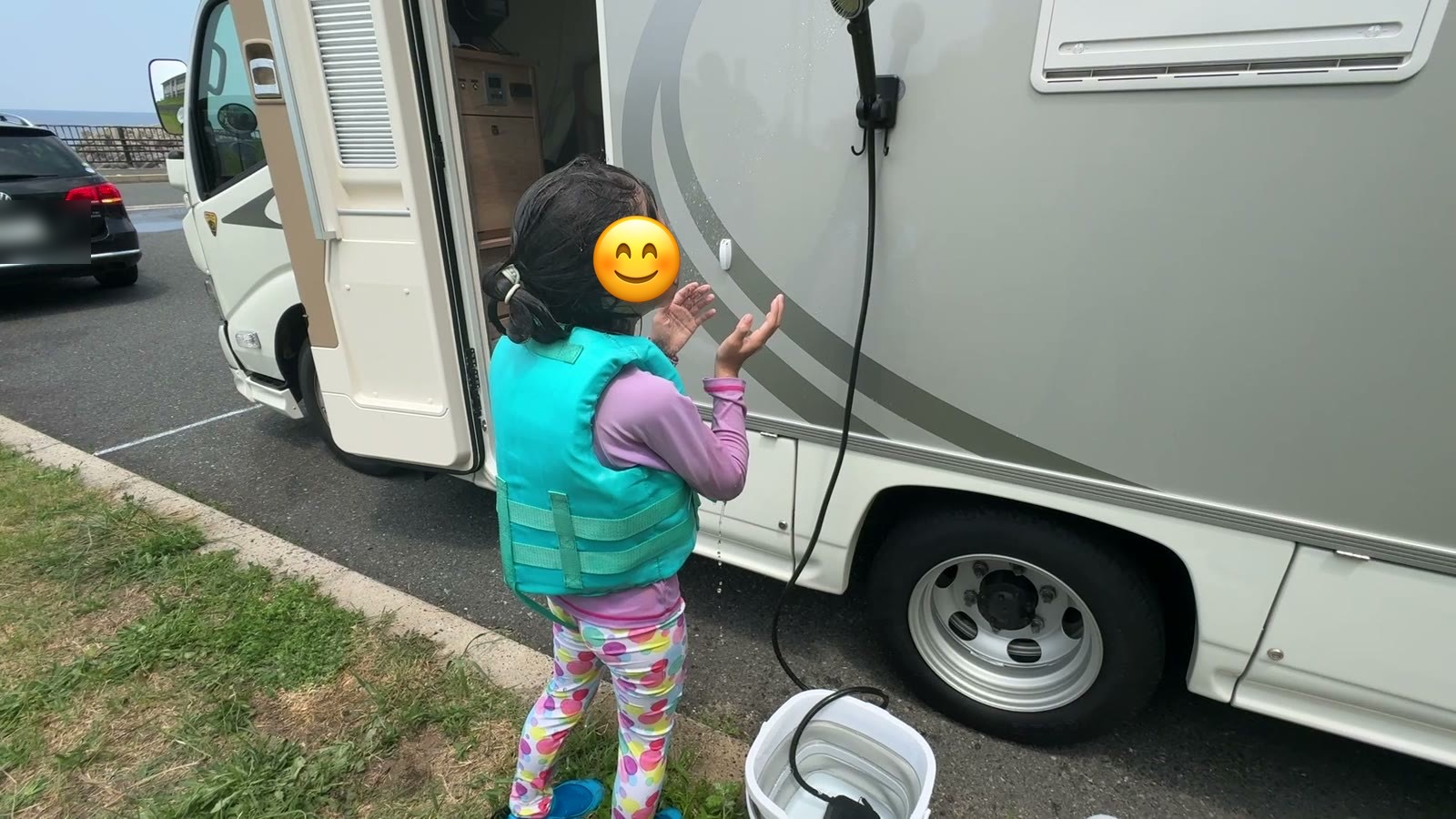 シャワーで流し終わってキャンピングカーの横に立つ娘